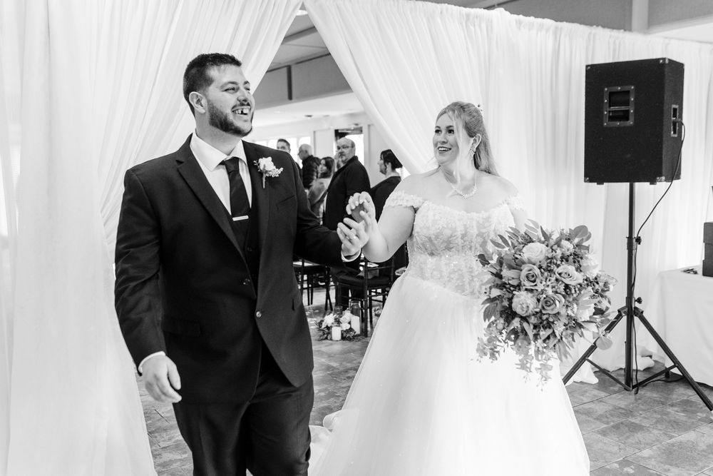 A joyful couple shares a happy moment during their wedding ceremony in a white draped venue.