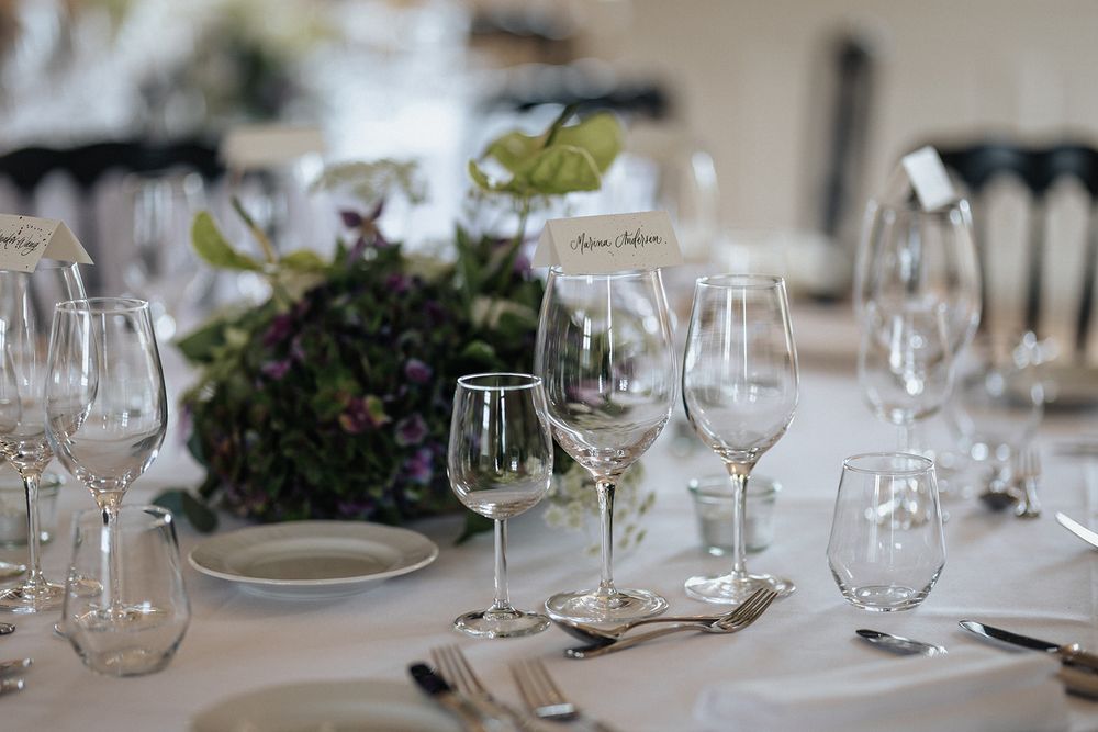 Elegant table setting with crystal wine glasses and white plates arranged for a formal dining event.
