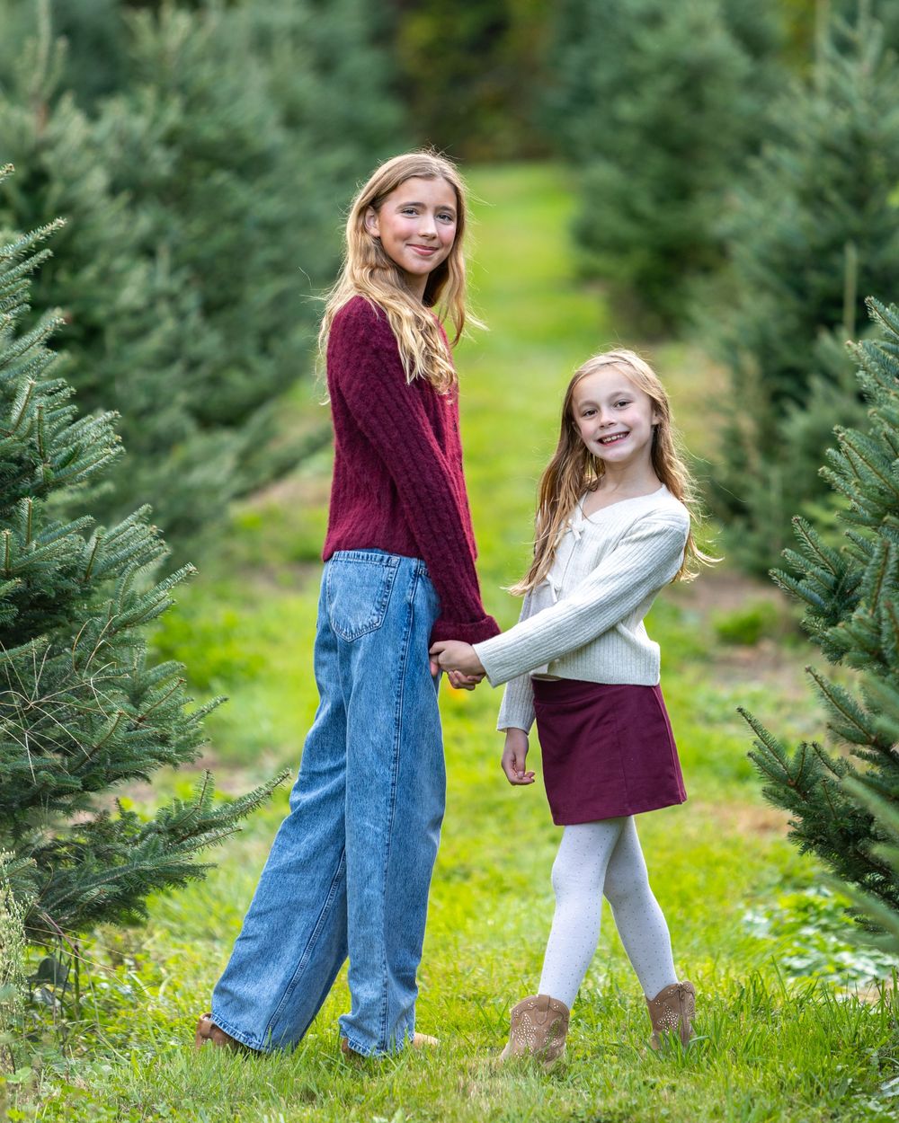 Siblings pose in front of a tree at a Christmas Tree Farm in Metrowest of MA at holiday family photography session by Lisa West Photography.