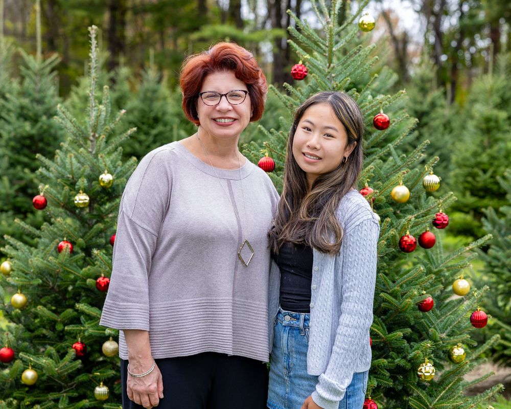 A family pose in front of a tree at a Christmas Tree Farm in Metrowest of MA at holiday family photography session by Lisa West Photography.