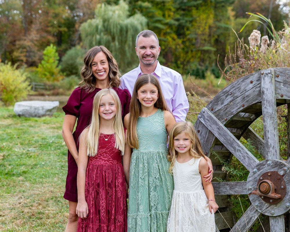 A family poses at a Christmas Tree Farm in Stow, MA (Metrowest) at holiday family photography session by Lisa West Photography.
