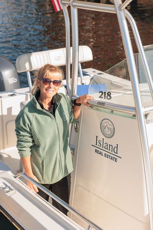 Woman in green jacket smiling on an Island Real Estate branded boat on the water.