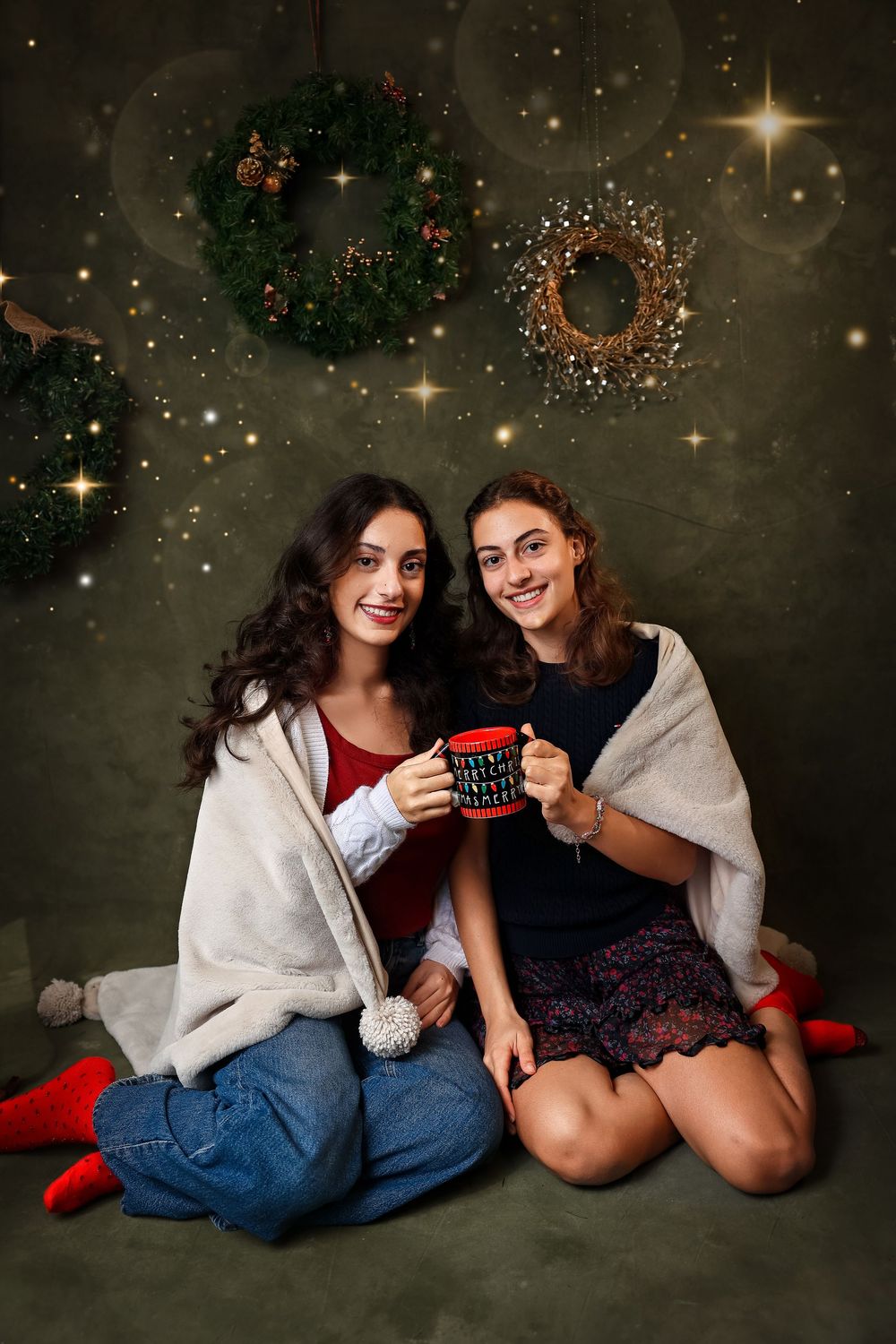 Two friends share cozy holiday moments with hot drinks and festive decor against a starry backdrop.