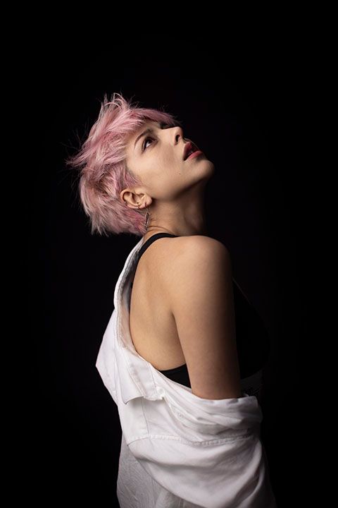 Artistic portrait series showing person with pink hair against black background.