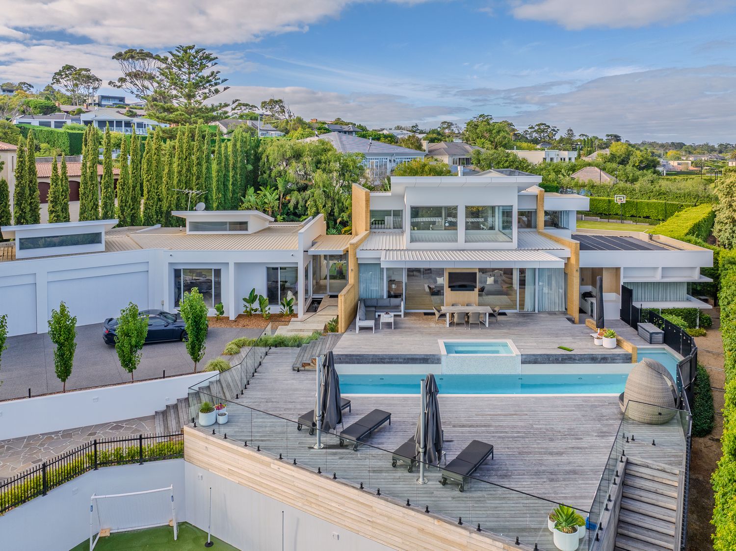 Luxury modern home with a large swimming pool, outdoor entertaining area, and panoramic suburban views.