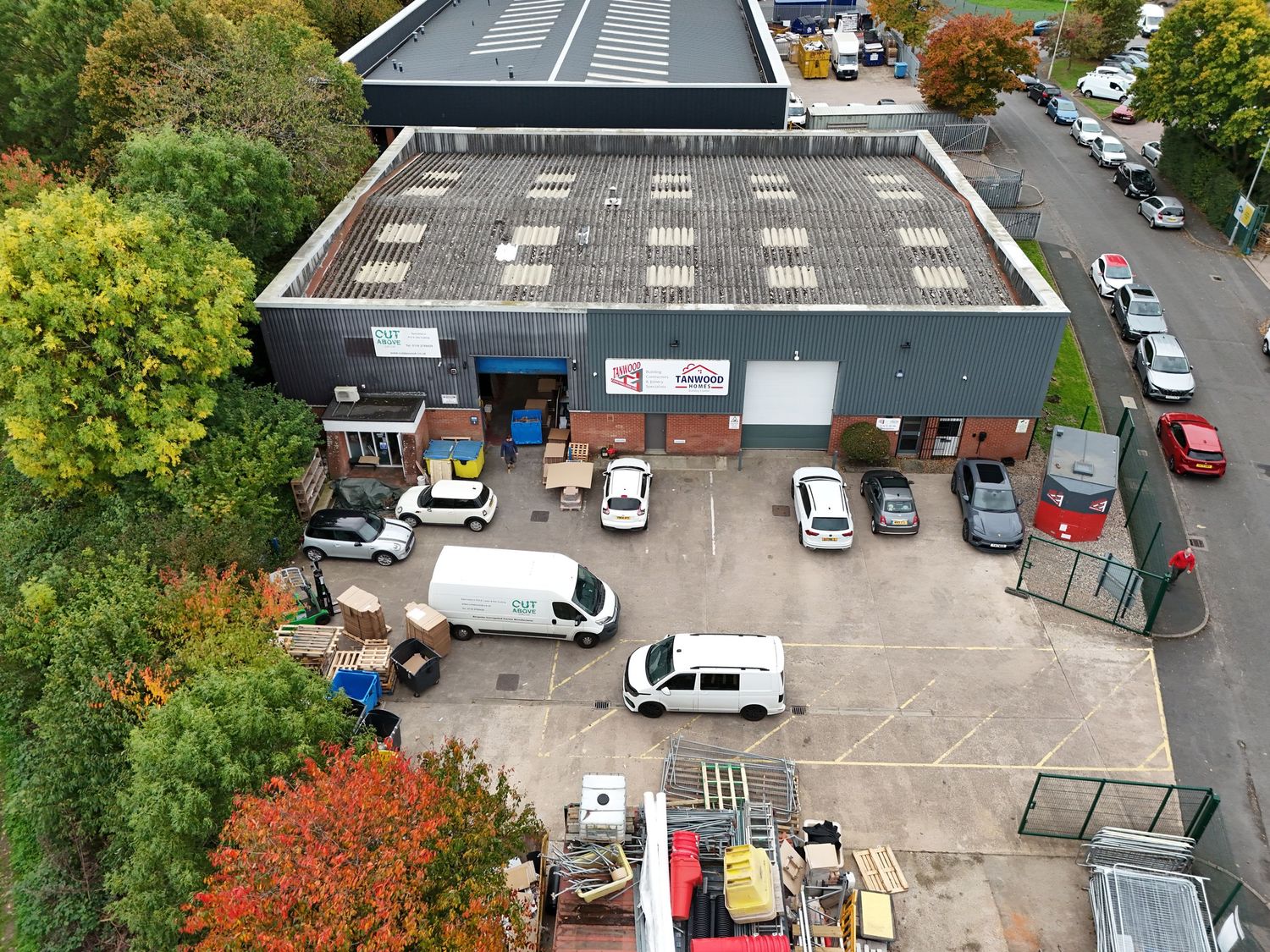 Aerial view of a parking lot with cars surrounded by autumn trees and buildings.