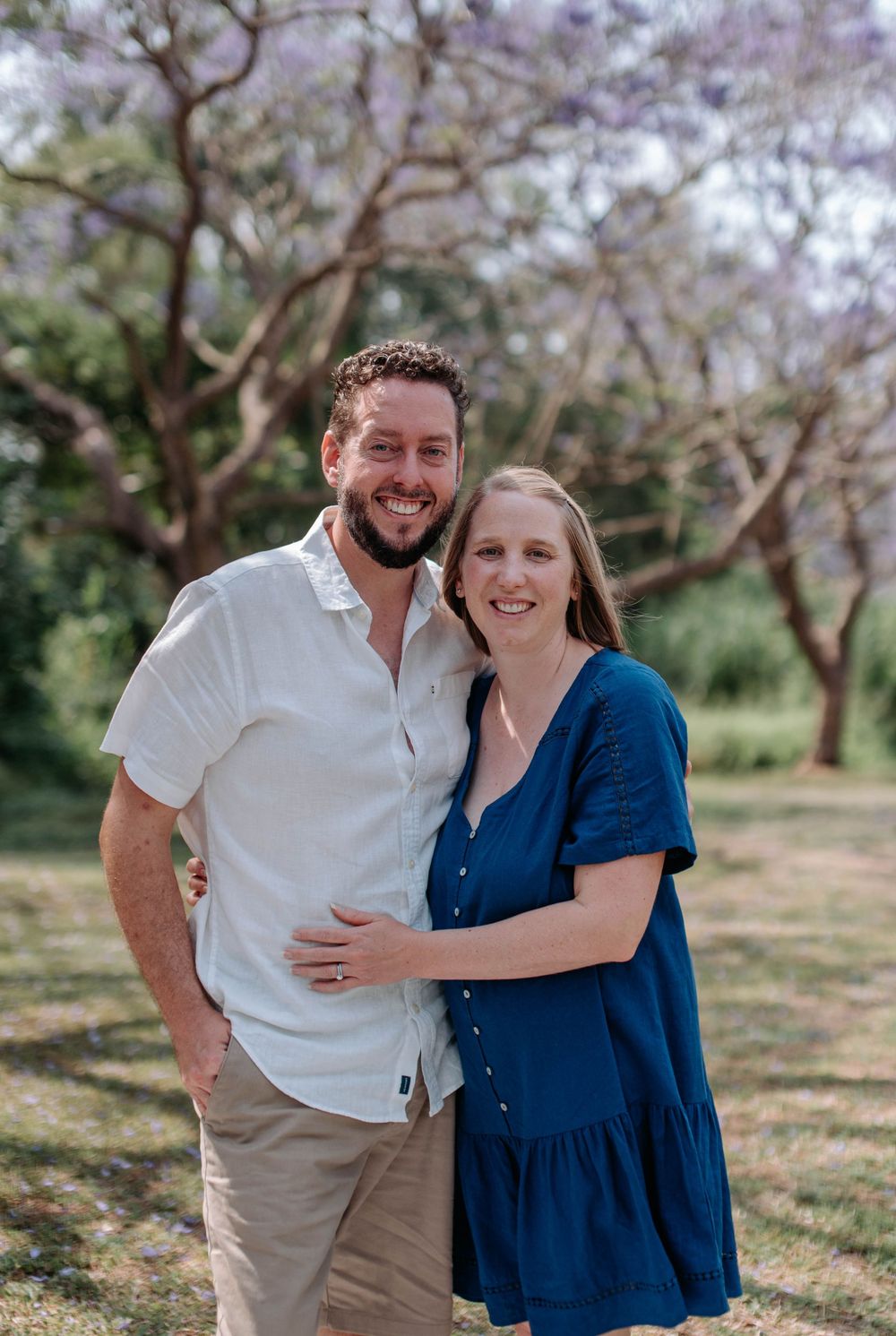 A couple shares joyful moments together in a spring garden setting with blooming trees in the background.