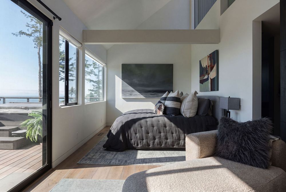 Modern beachfront bedroom with floor-to-ceiling windows, plush bedding, and stunning ocean views.