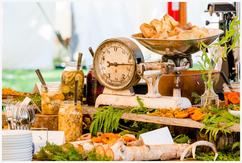 Rustic food display with vintage clock, fresh appetizers, and decorative table settings at an outdoor event.