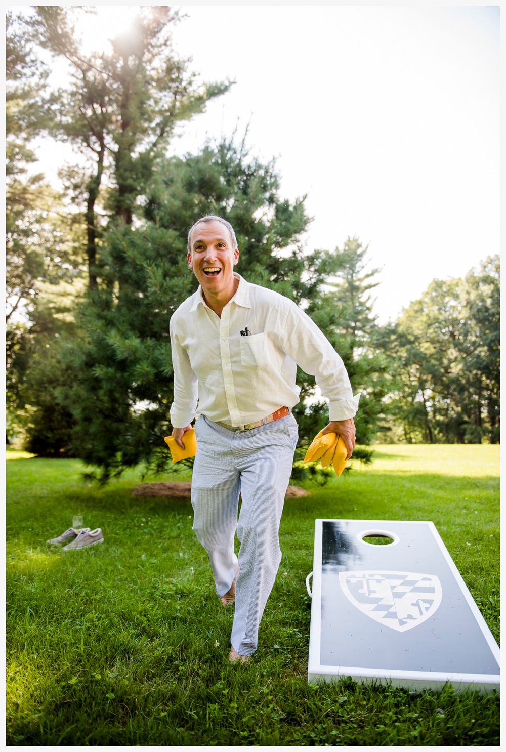 Person playing cornhole game on sunny lawn with white game board.