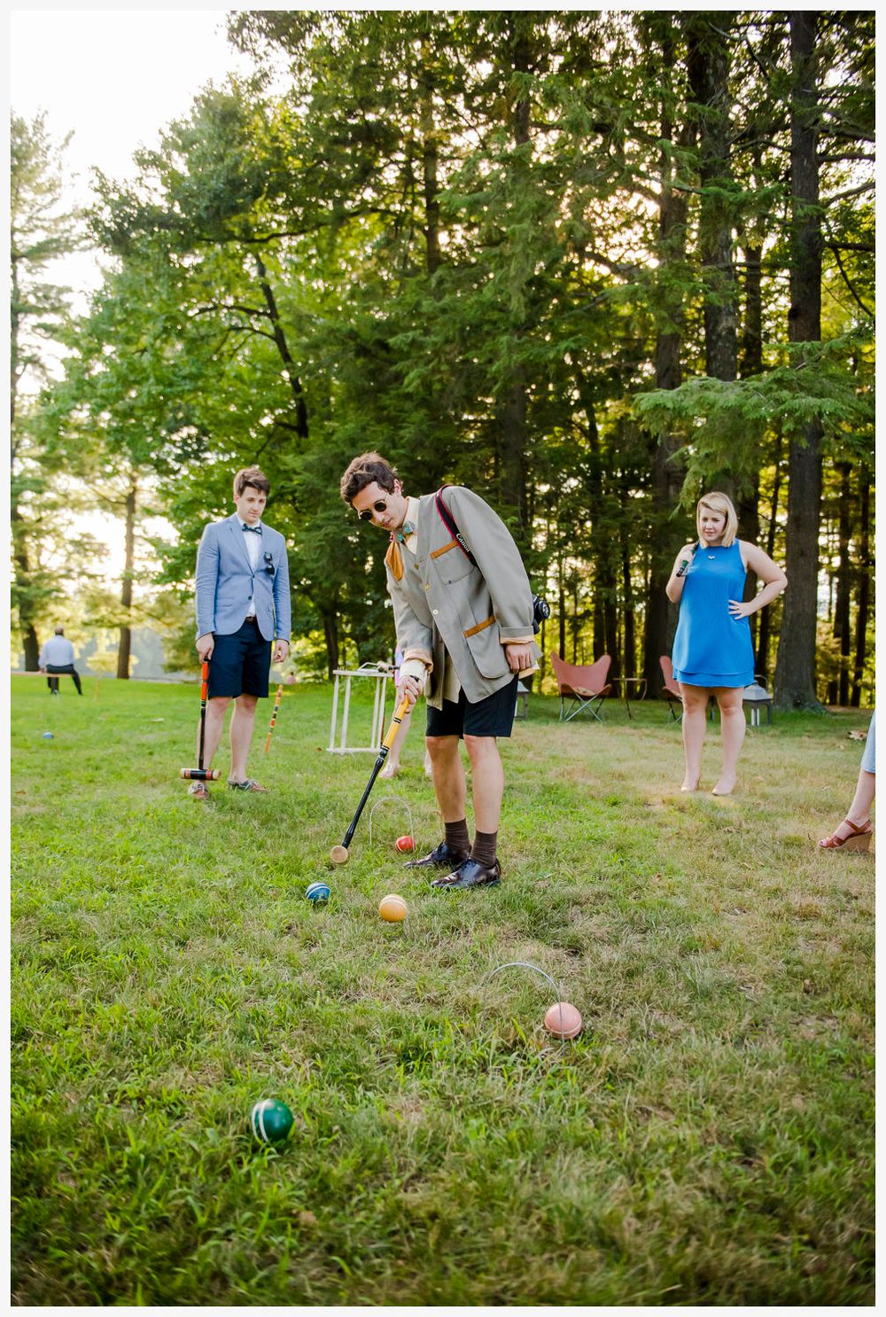 Wedding guests playing croquet on a grassy lawn during outdoor reception.