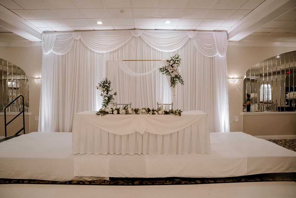 White draped fabric and decor create an elegant wedding reception venue setup with soft lighting.