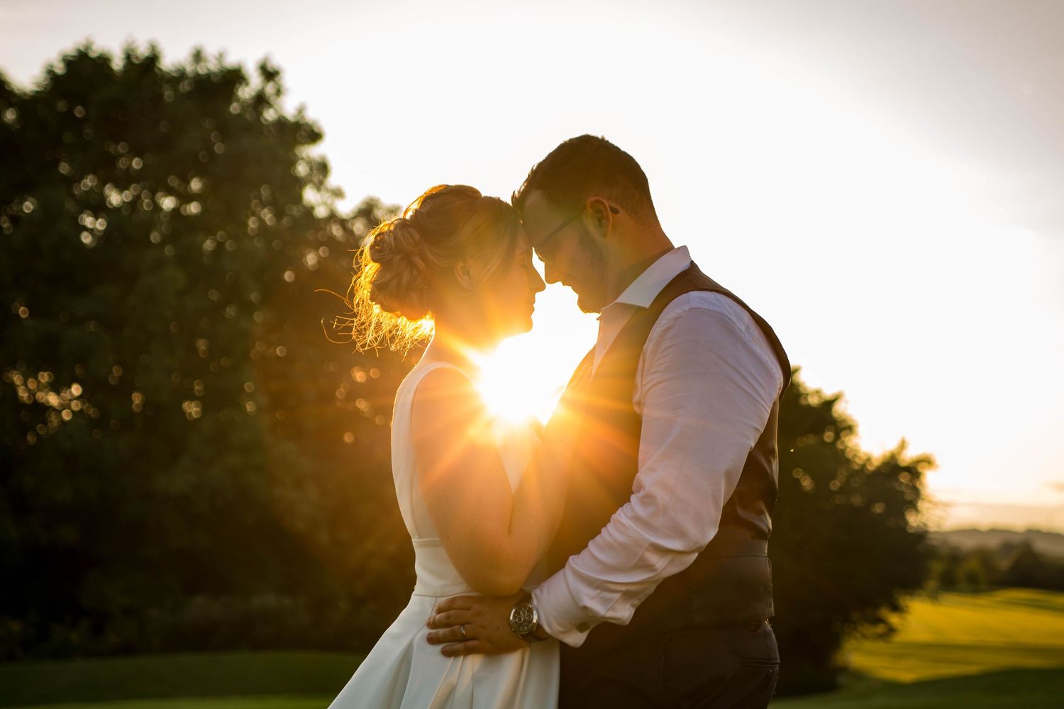 A romantic sunset silhouette of newlyweds embracing in a golden field.