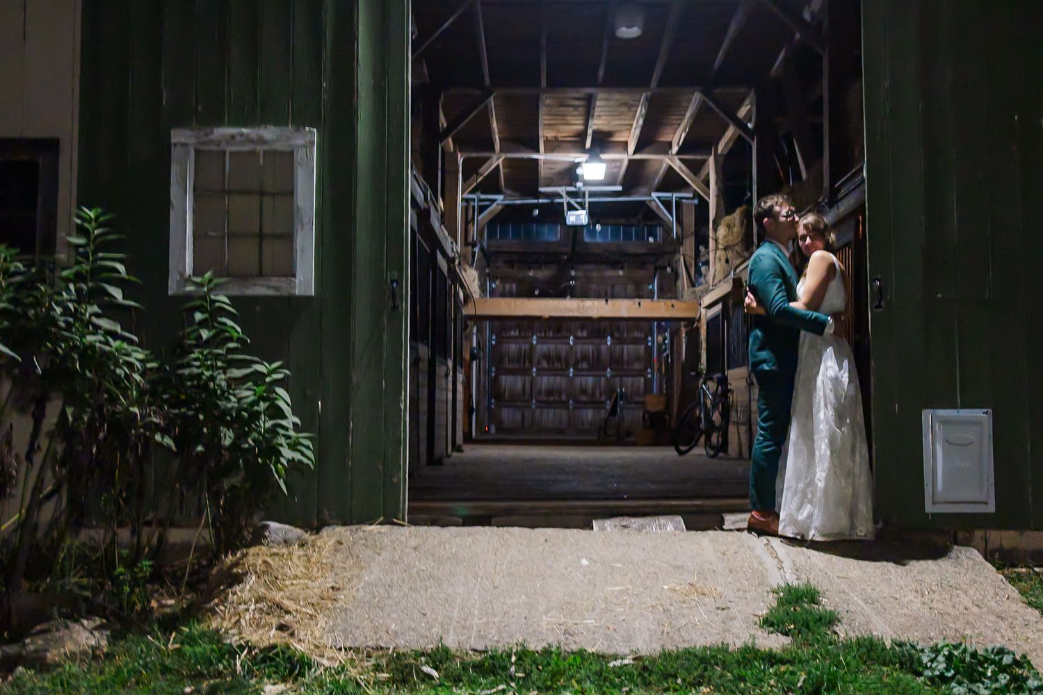 A couple stands together on a dimly lit porch at night with soft lighting creating a romantic atmosphere.
