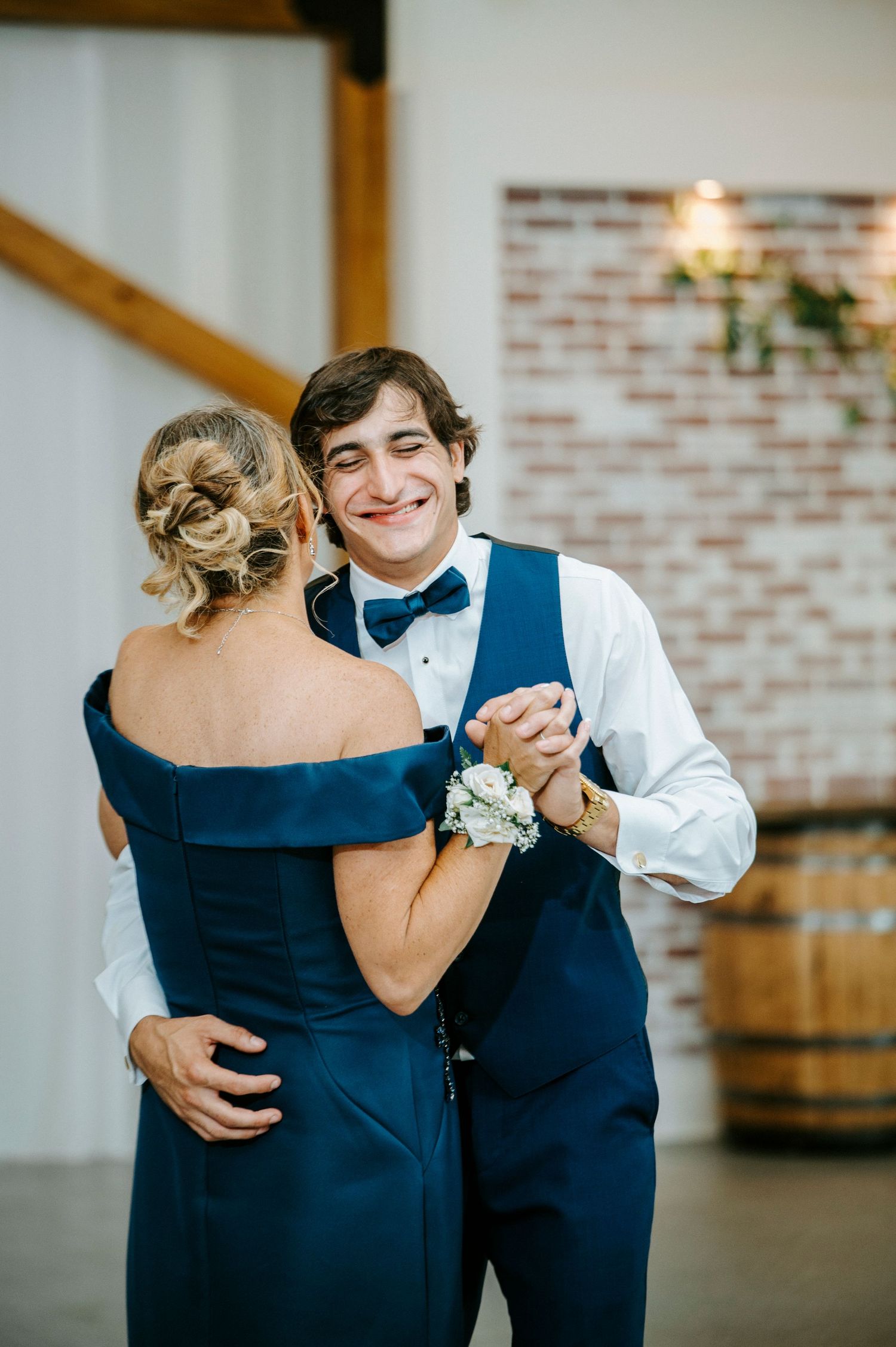 A series of intimate dance photos showing a mother-son dance at a wedding reception in a rustic venue.