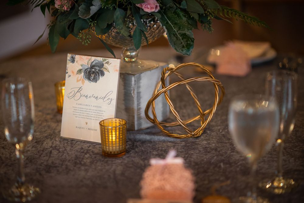 Wedding reception table detail with menu card, gold geometric decor and floral centerpiece.