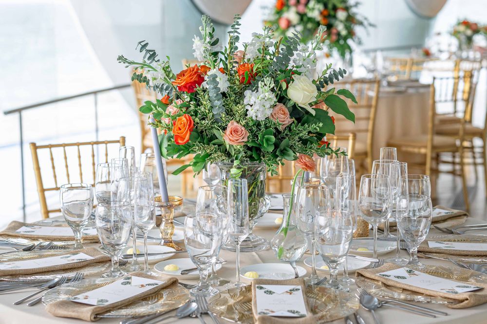 Elegant wedding table setting with colorful floral centerpiece, crystal glassware and gold chiavari chairs.