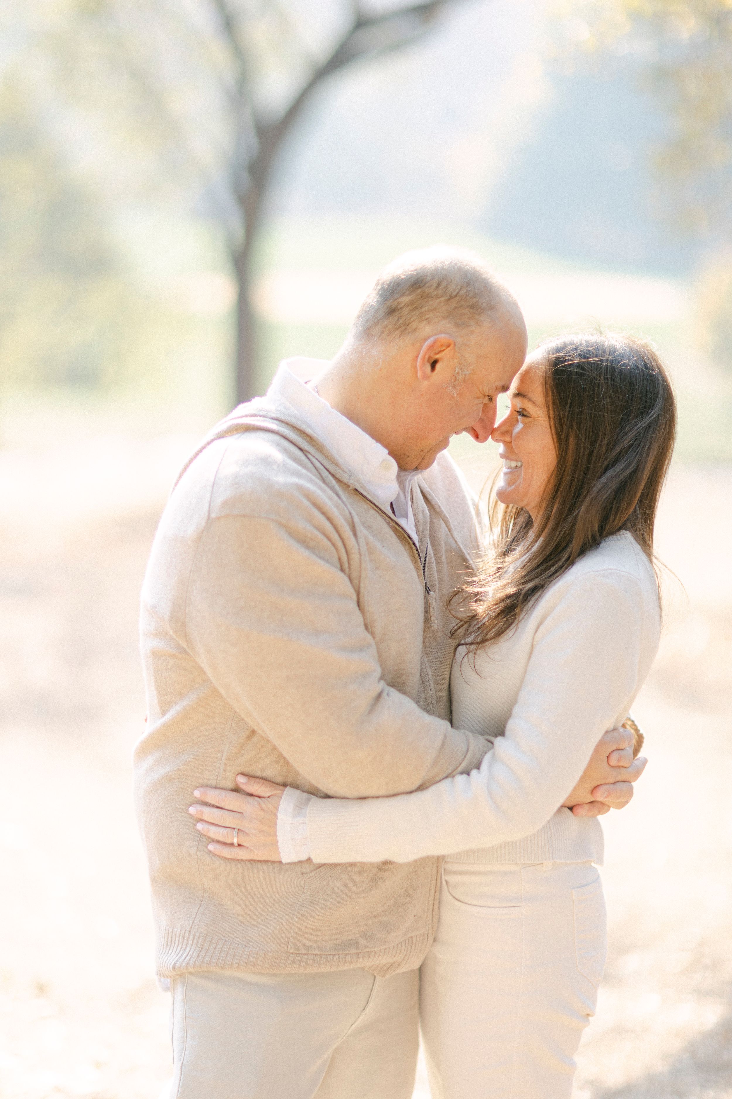 Intimate portrait of couple in beige clothing sharing a tender moment outside.