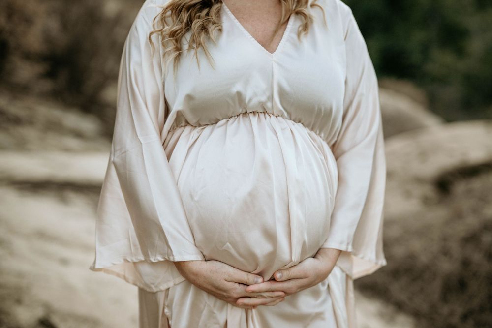 A close-up view of a white flowing maternity dress with gathered detail at the waist.
