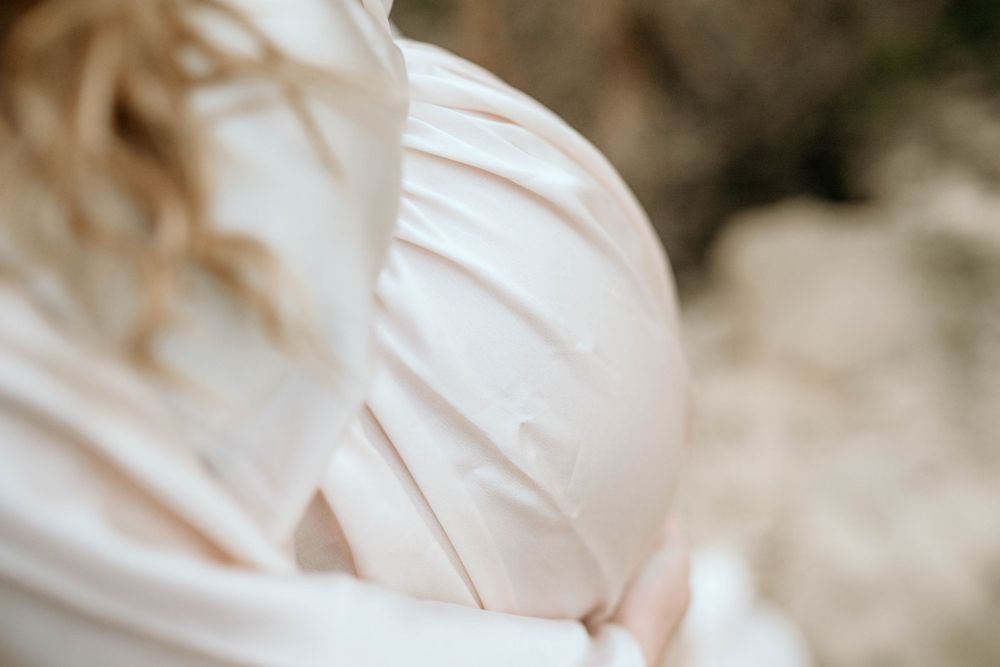 Close up detail of gathered fabric on a cream colored maternity dress.