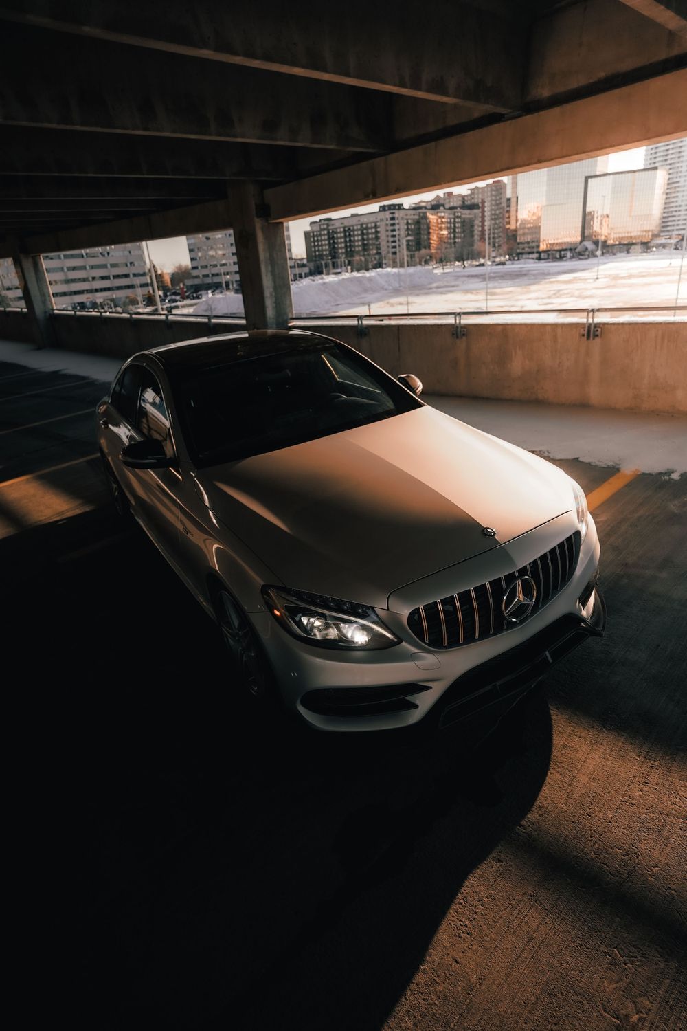 Silver Mercedes-AMG C-Class parked in shadowy concrete parking structure. Mtlshutter photography