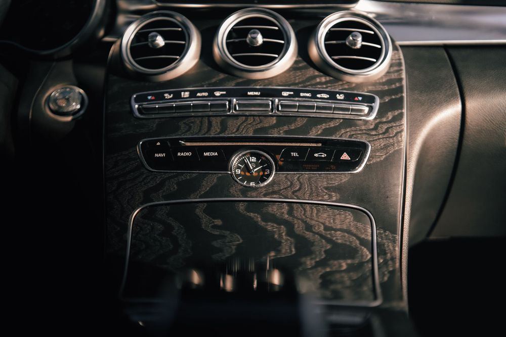 Close-up view of a luxury car dashboard showing circular air vents and climate controls in metallic finish. Mtlshutter photography