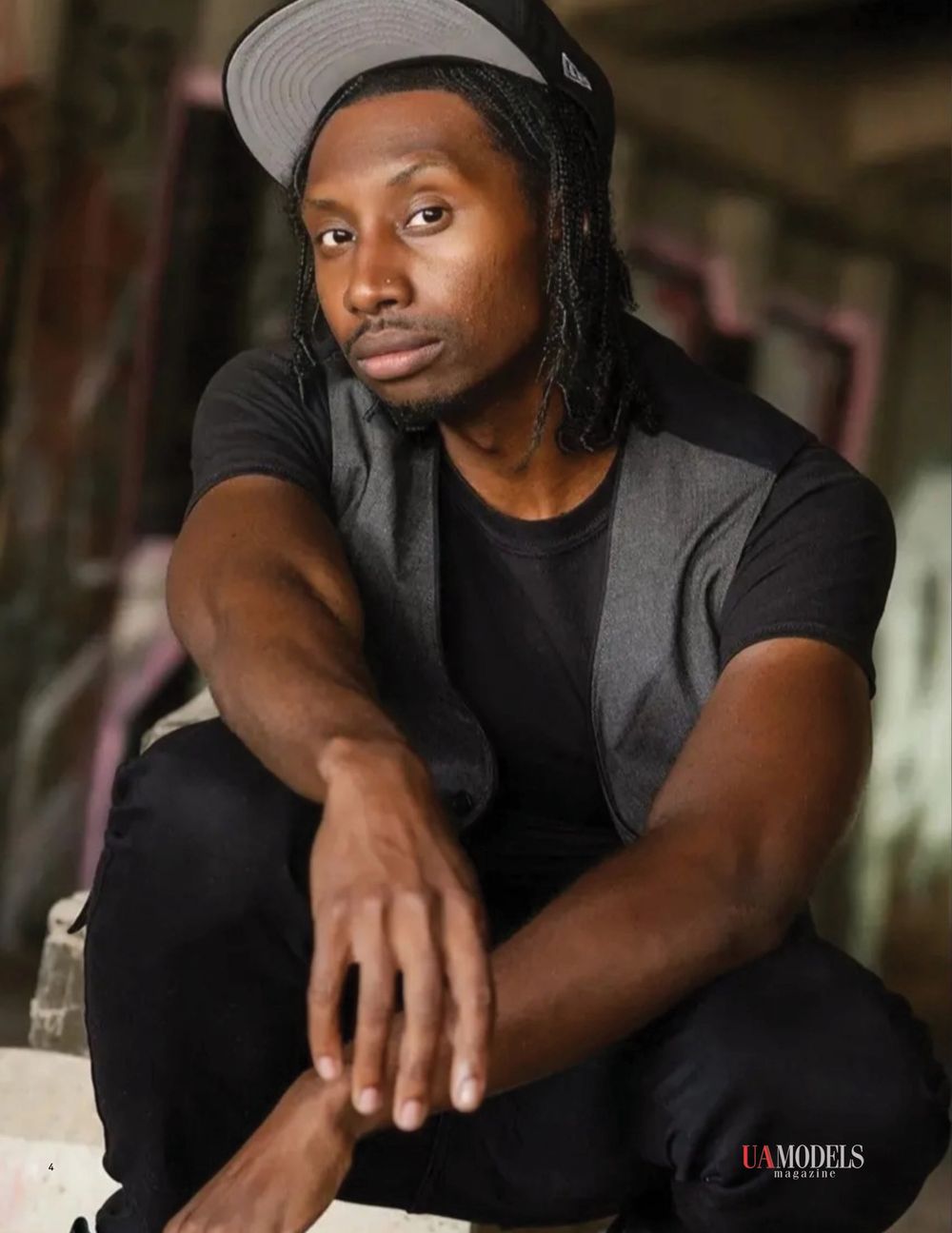 Portrait of a model in casual black attire and grey cap.