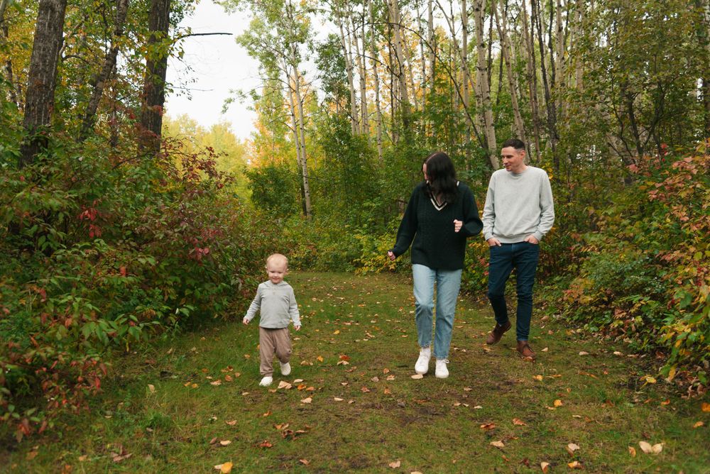 Family walking together on a wooded trail during autumn.
