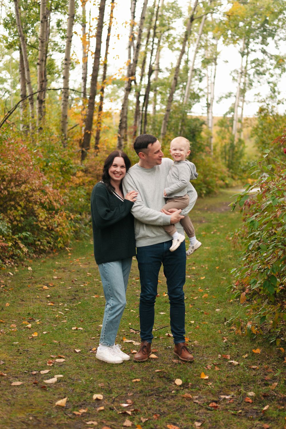Natural family photo on a tree-lined path during autumn.