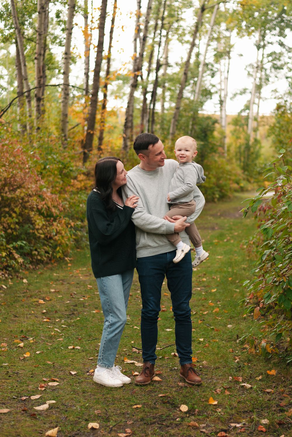 Family portrait in casual attire against vibrant fall foliage.