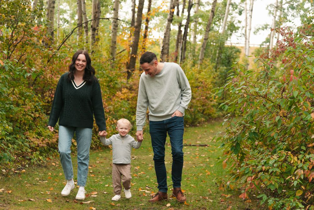 Family walking together on an autumn path surrounded by colorful foliage.