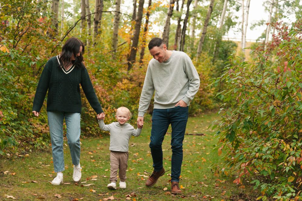A family enjoys an autumn walk together on a wooded trail.