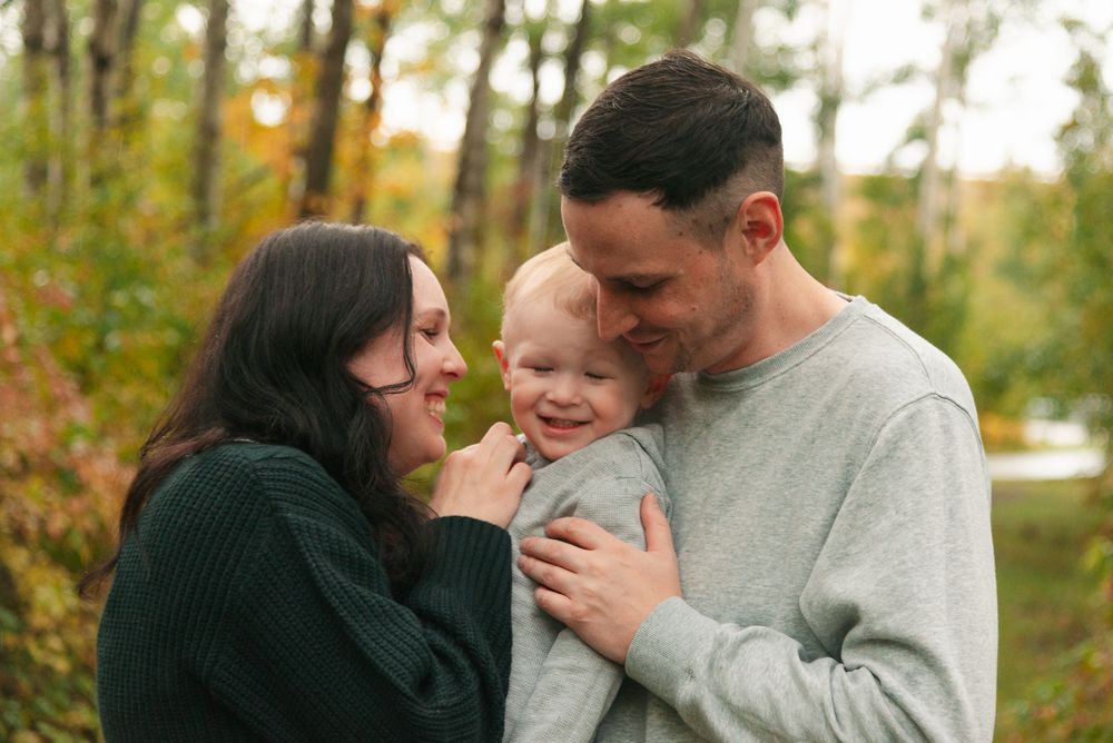 Intimate family portrait with warm expressions against autumn foliage.