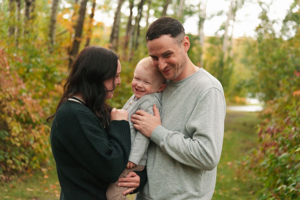 Candid family photo showing joyful interaction in a fall woodland setting.