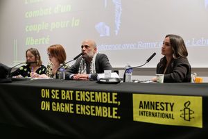 Amnesty International panel discussion with four speakers at a conference table with French slogan banner.