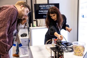 Researchers examine photon streaming equipment at a DLS technology demonstration booth at a scientific conference.