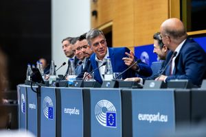 European Parliament officials engage in discussion at a formal EU meeting, with europarl.eu branding visible.