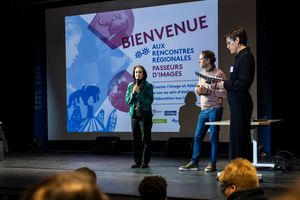 Three speakers present at Bienvenue aux Rencontres Régionales Passeurs d'Images event on stage with projector screen.