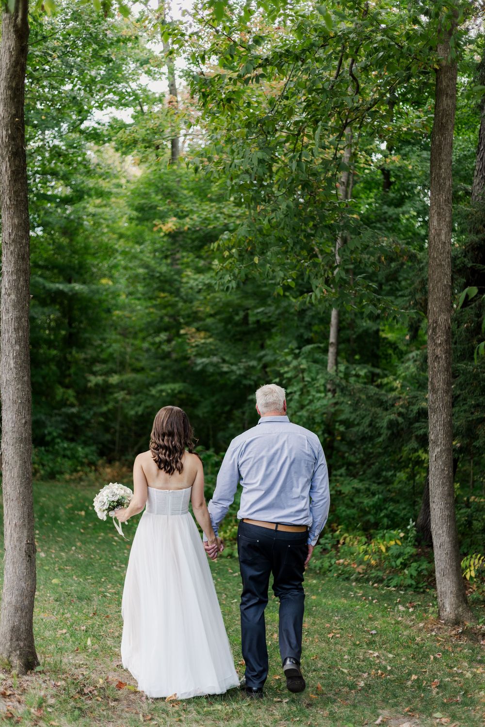 Candid wedding photo of bride and groom walking through their backyard during their sunset wedding near woodstock, ontario.