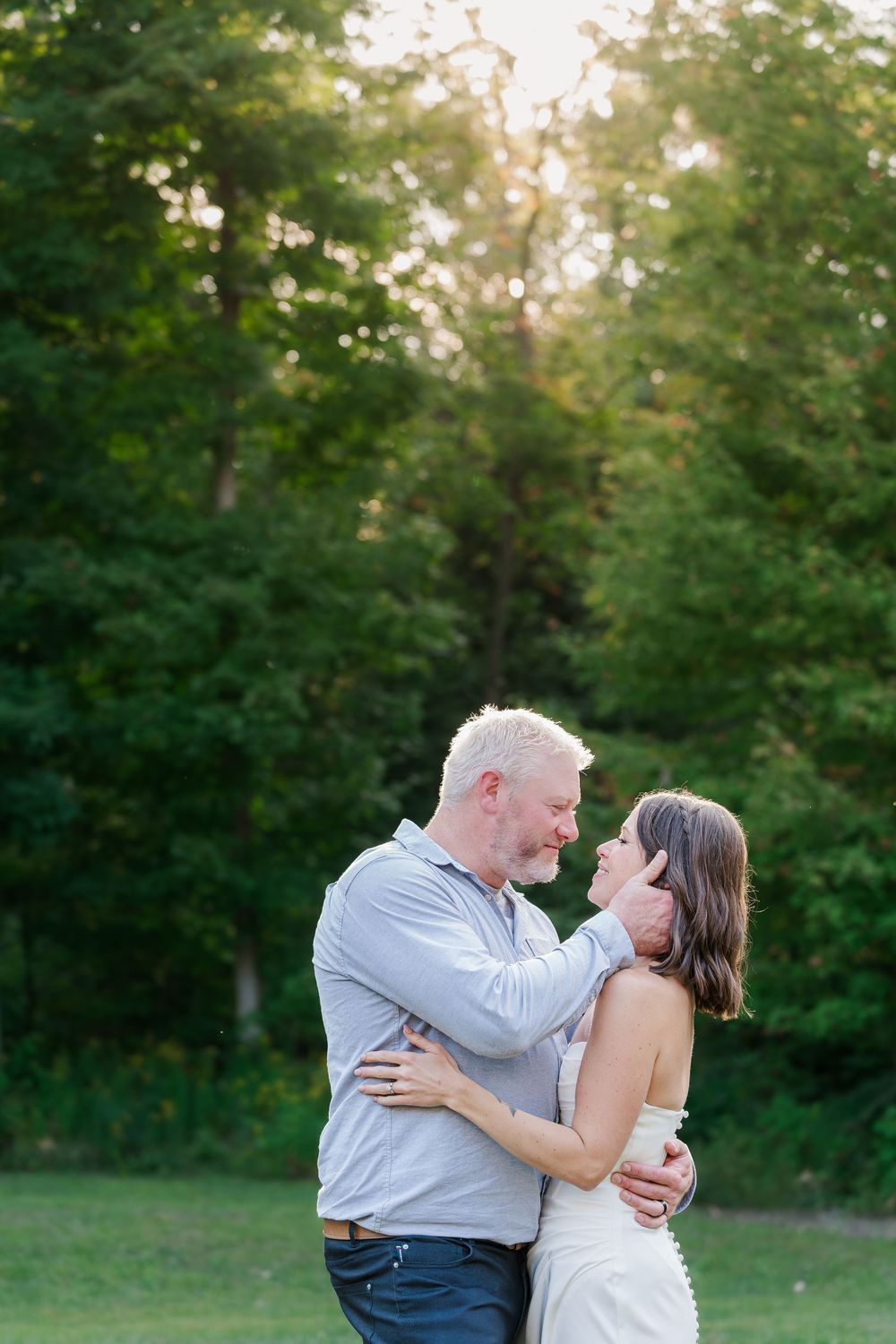 Groom pulls his bride in for a kiss during sunset at the summer backyard wedding near woodstock, ontario.