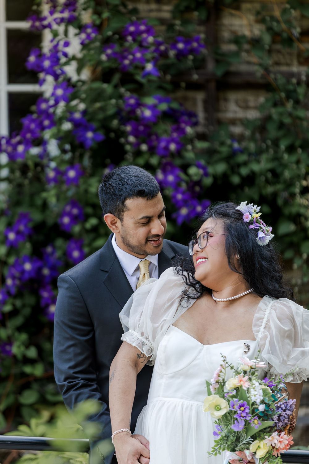 Bride and groom look lovingly at each other standing in a garden during their summer wedding photos near woodstock, ontario.