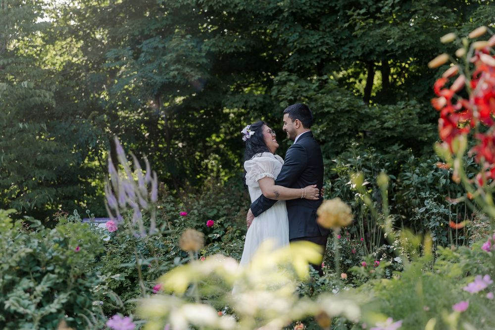 Bride and groom embrace each other surrounded by a lush garden during their wedding photos near woodstock, ontario.