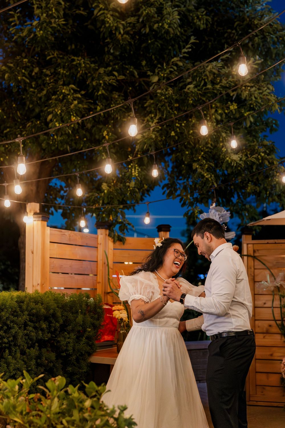 Bride and groom dance under twinkle lights during their outdoor evening wedding reception near woodstock, ontario.