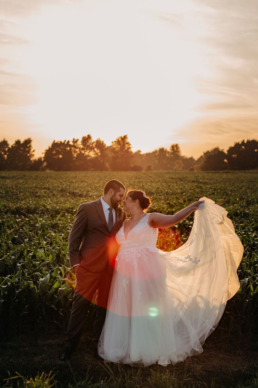 Bride and groom stand in a field during sunset photos on their summer wedding near woodstock, ontario.