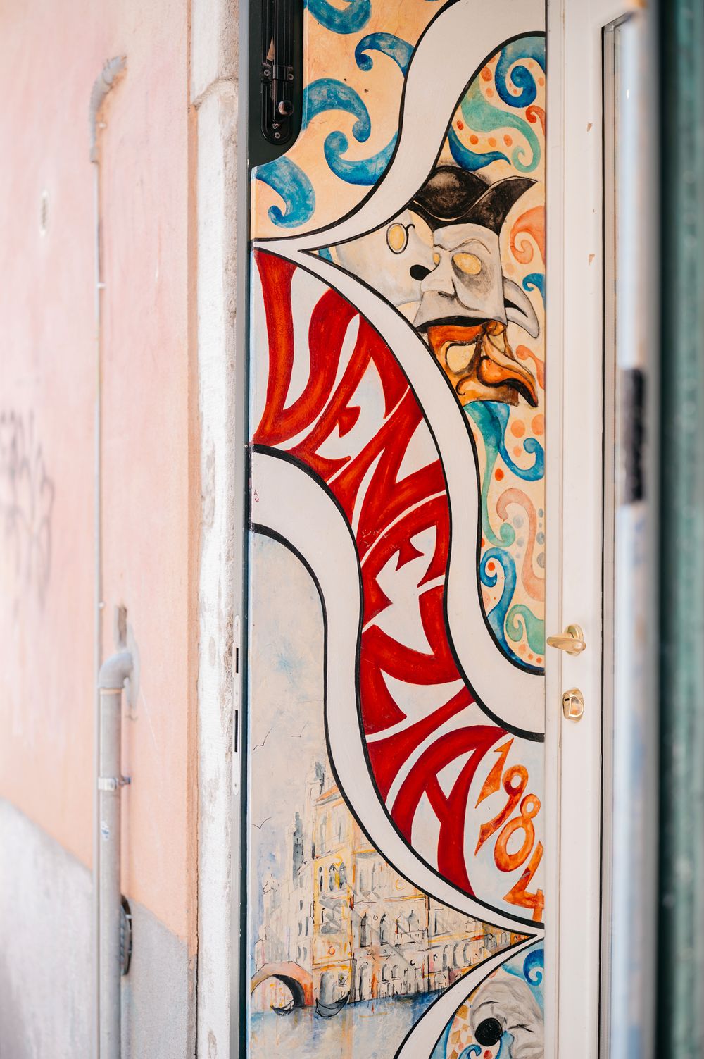 Colorful painted door featuring the word Venezia in red letters with ornate swirling designs in Venice, Italy.