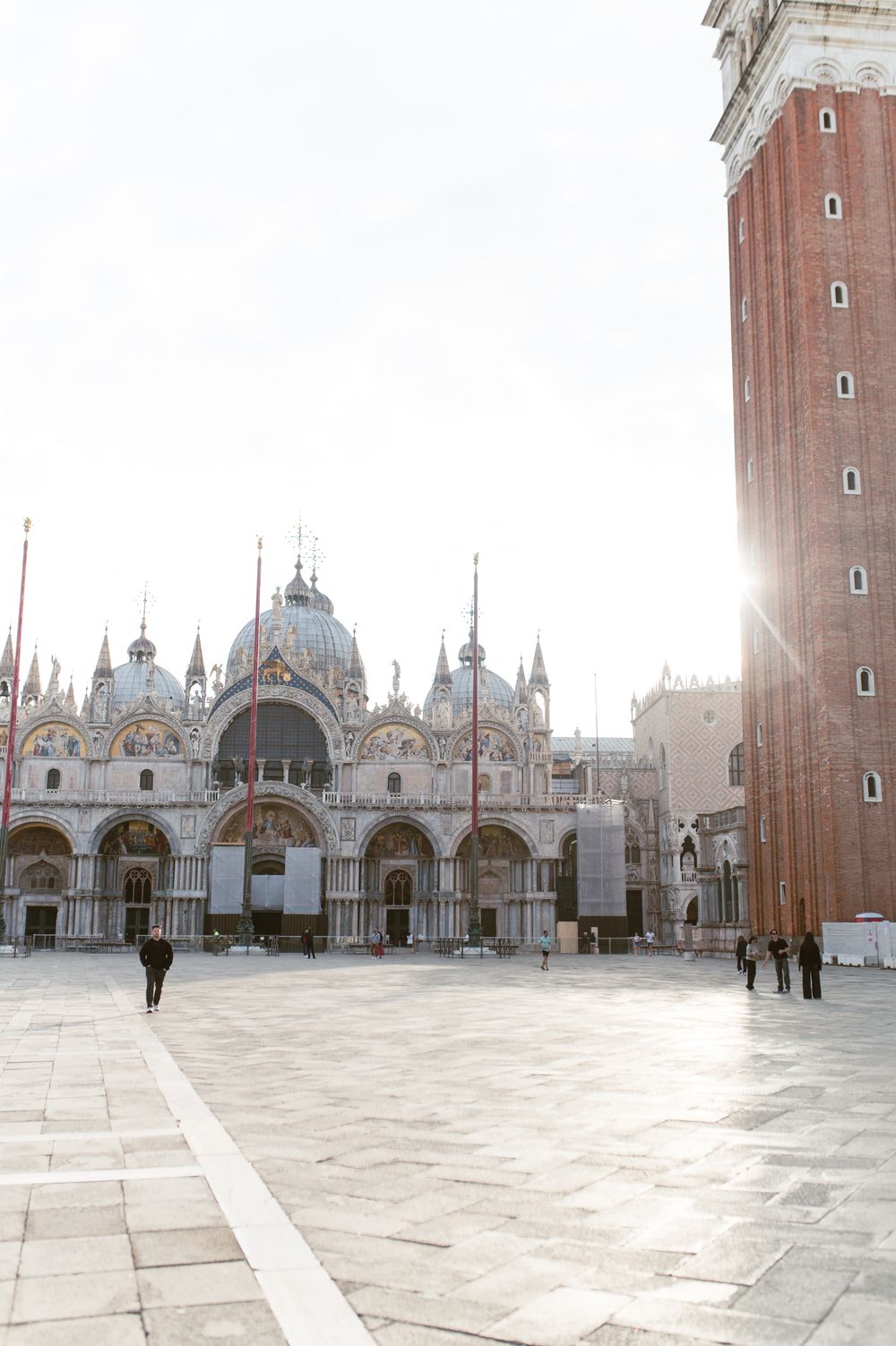 Sun-drenched St. Marks Square with the iconic Byzantine Basilica and Campanile tower in Venice, Italy.
