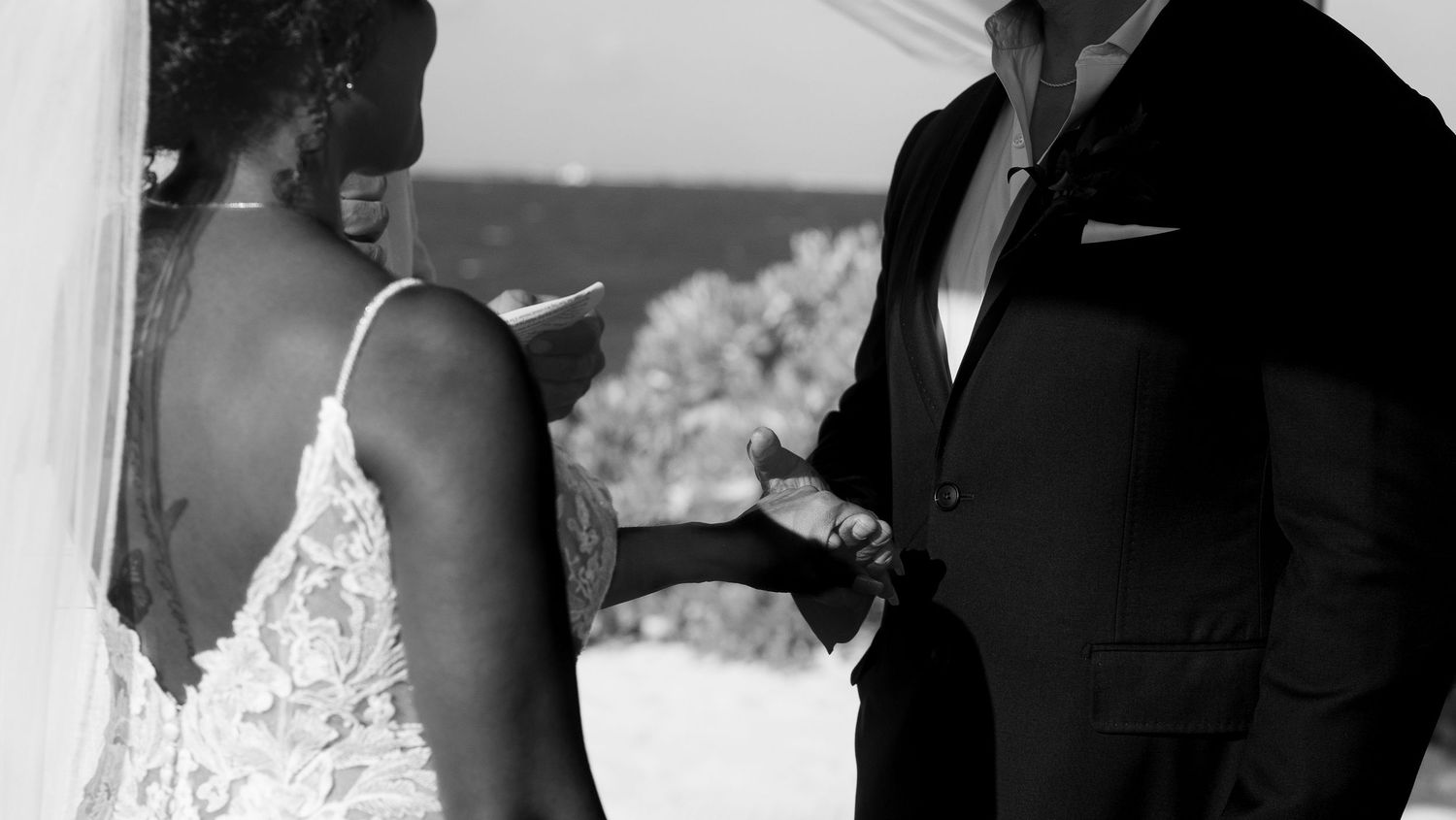 Beachside wedding ceremony under white fabric canopy with ocean view.