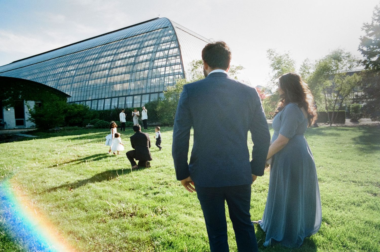A romantic moment captured on color film in a lush greenhouse wedding venue with tropical plants and natural light.