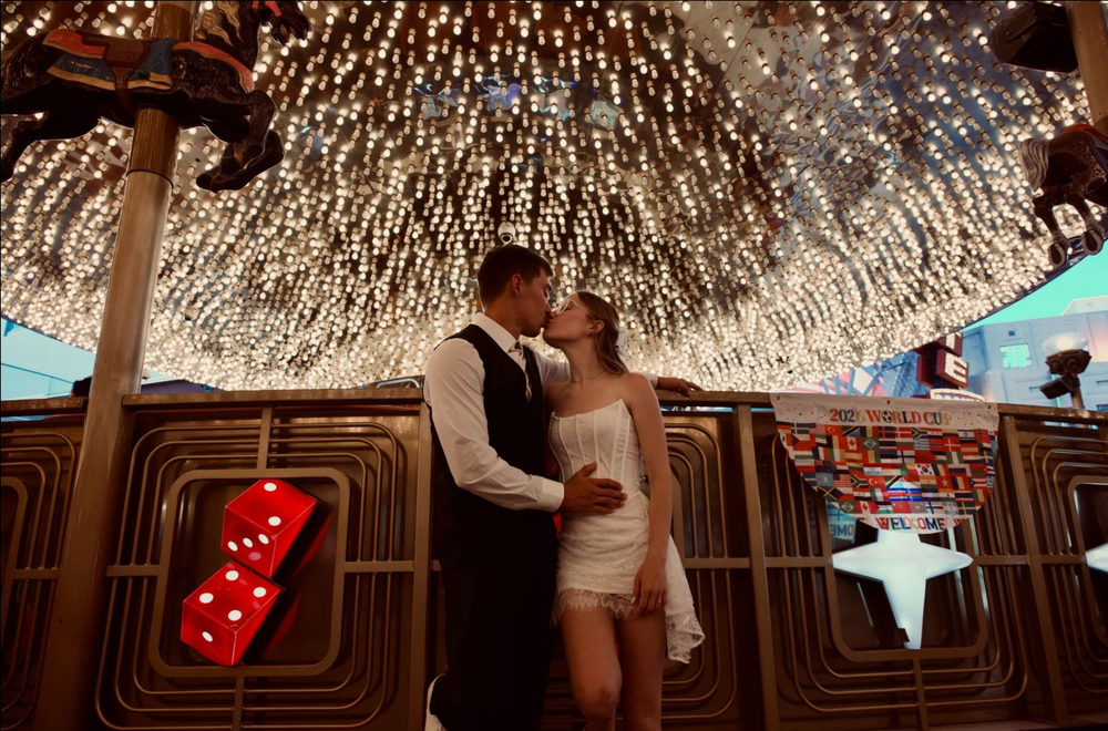 Couple sharing a romantic kiss under a dazzling ceiling of twinkling lights in a glamorous Las Vegas venue.
