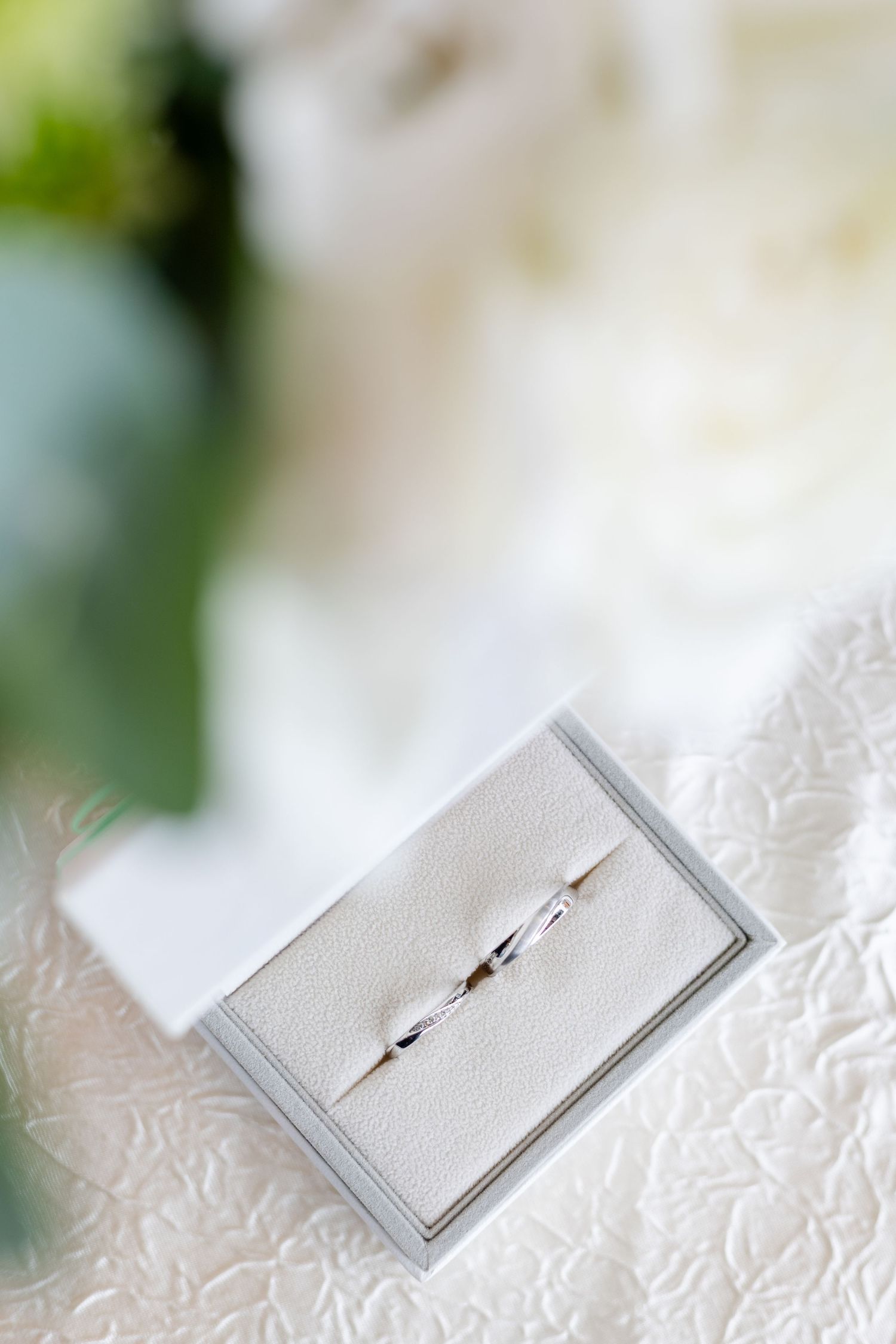 wedding photographer in singapore. bridal details, wedding ring in luxurious grey satin ring holder and white roses. bright airy photographs